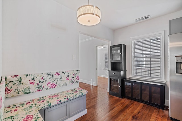 living room with dark wood-style floors, visible vents, and baseboards