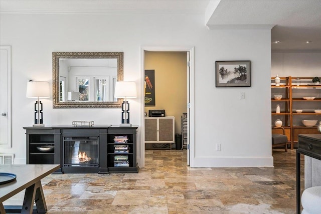 interior space featuring a glass covered fireplace, crown molding, stone finish floor, and baseboards