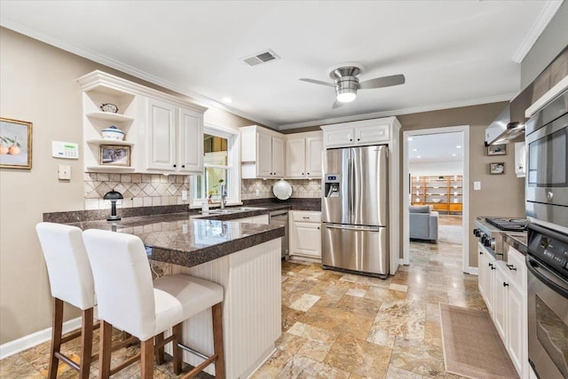 kitchen with a breakfast bar area, visible vents, a peninsula, ceiling fan, and appliances with stainless steel finishes