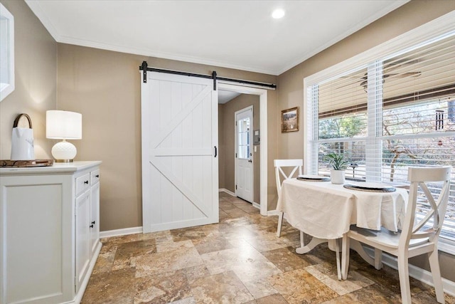 dining area featuring a barn door, baseboards, and ornamental molding