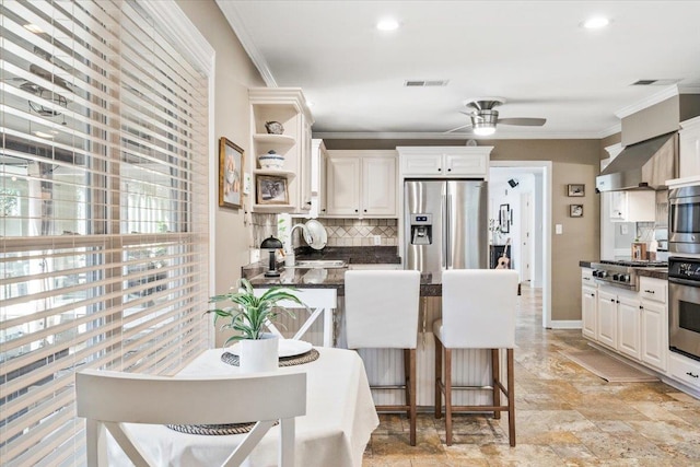 kitchen with ceiling fan, ornamental molding, appliances with stainless steel finishes, dark countertops, and tasteful backsplash