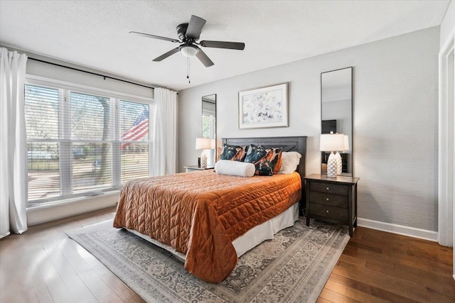 bedroom featuring baseboards, a textured ceiling, a ceiling fan, and hardwood / wood-style flooring