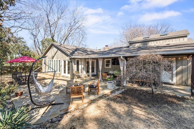 rear view of property with a patio area, outdoor dining area, french doors, and a chimney