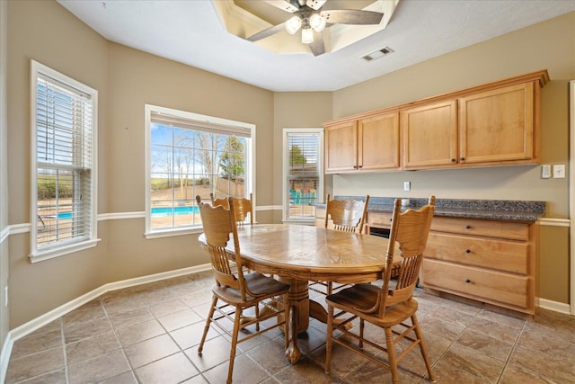 dining space featuring visible vents, a ceiling fan, a tray ceiling, and baseboards