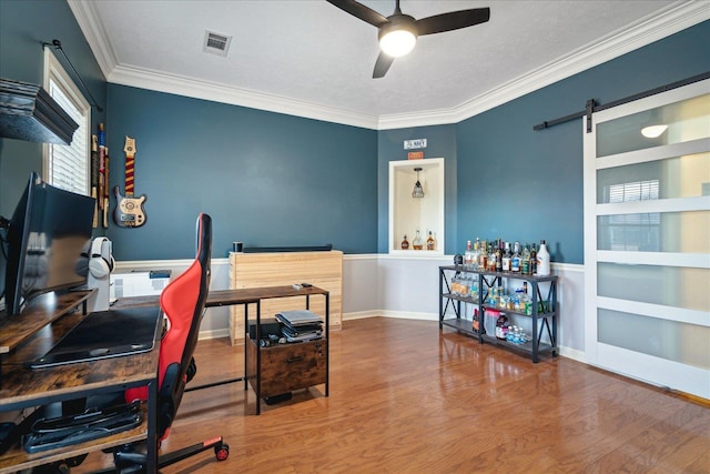 office area with wood finished floors, baseboards, a ceiling fan, visible vents, and ornamental molding