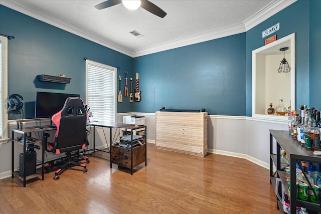 office with ceiling fan, visible vents, wood finished floors, and ornamental molding