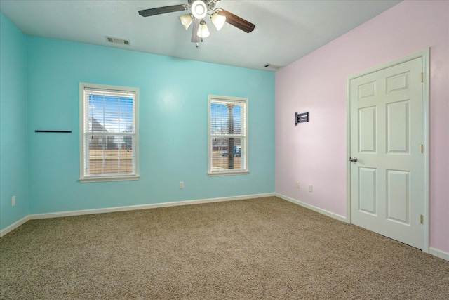 carpeted empty room with visible vents, baseboards, and ceiling fan