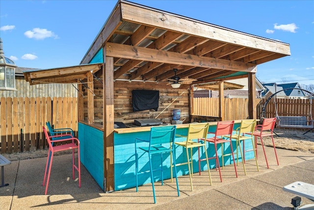 view of patio featuring outdoor dry bar and fence