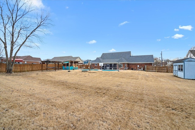 view of yard with a storage shed, a fenced backyard, a fenced in pool, and an outdoor structure