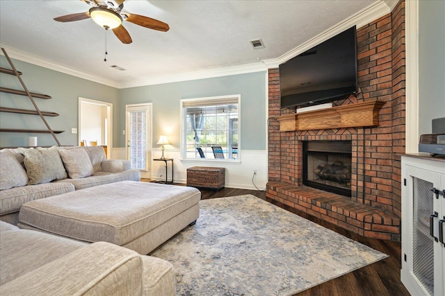 living room featuring visible vents, ornamental molding, a ceiling fan, wood finished floors, and a brick fireplace