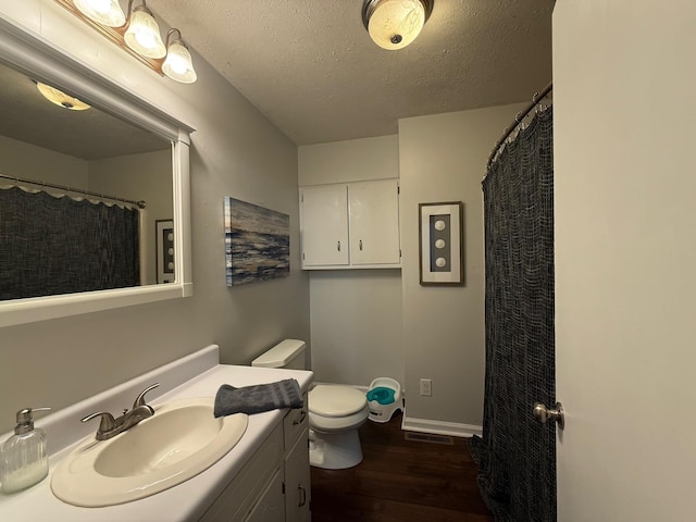 bathroom with vanity, wood finished floors, visible vents, a textured ceiling, and toilet