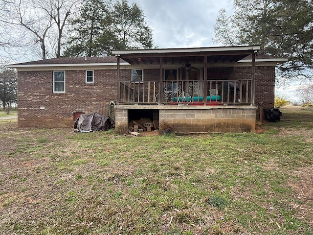 rear view of property with a yard, a ceiling fan, brick siding, and crawl space