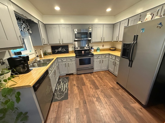 kitchen with dark wood-type flooring, gray cabinets, a sink, stainless steel appliances, and light countertops