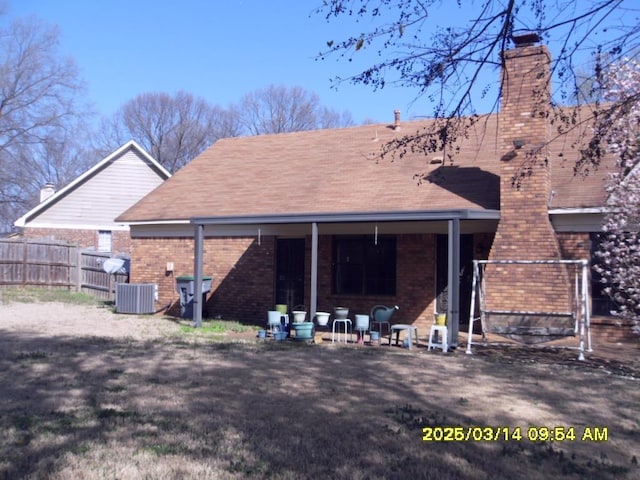 back of house with cooling unit, fence, brick siding, and a chimney