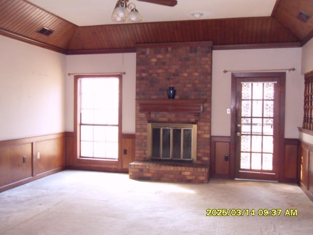 unfurnished living room featuring carpet flooring, wainscoting, a fireplace, and lofted ceiling