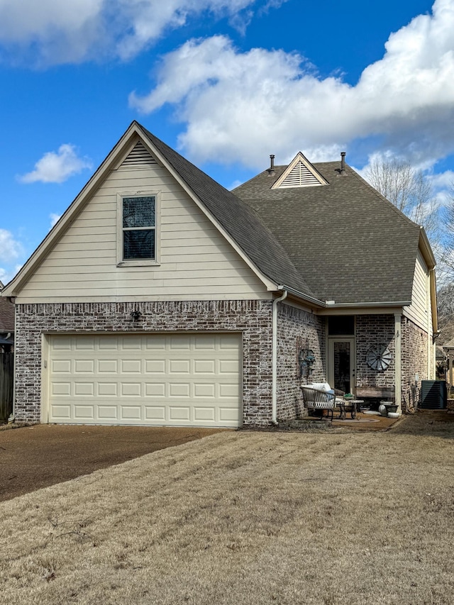 view of front of property with brick siding, central AC, driveway, and a shingled roof