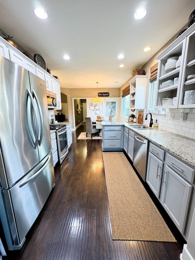 kitchen with dark wood-type flooring, gray cabinets, open shelves, a sink, and stainless steel appliances