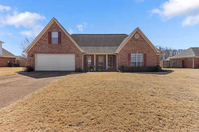 view of front of home with a front yard, central AC unit, fence, aphalt driveway, and brick siding