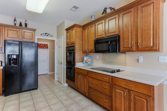 kitchen featuring light tile patterned floors, brown cabinetry, black appliances, light countertops, and a textured ceiling