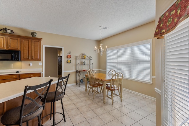 dining area with light tile patterned floors, baseboards, a notable chandelier, and a textured ceiling