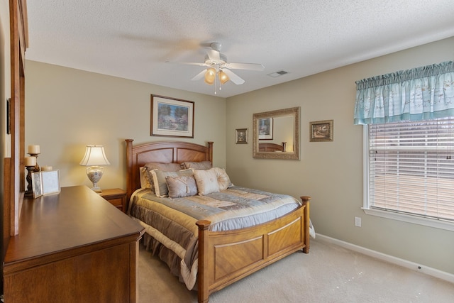 bedroom with visible vents, baseboards, light carpet, a textured ceiling, and a ceiling fan