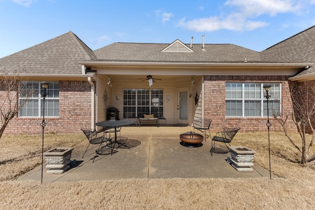 rear view of property with brick siding, ceiling fan, an outdoor fire pit, roof with shingles, and a patio