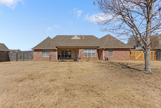 back of house with a gate, a fenced backyard, brick siding, and roof with shingles