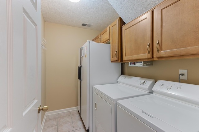 laundry room with visible vents, light tile patterned floors, cabinet space, washer and dryer, and a textured ceiling