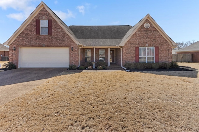 view of front facade with driveway, roof with shingles, an attached garage, a front lawn, and brick siding