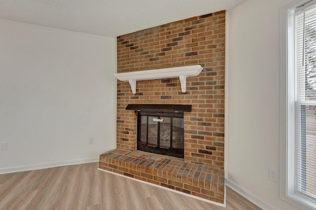 unfurnished living room featuring a fireplace, wood finished floors, and baseboards