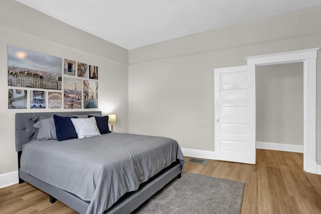 bedroom with wood finished floors, visible vents, and baseboards