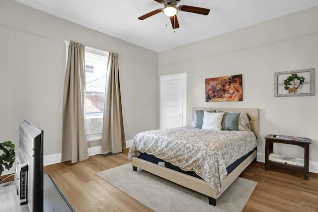 bedroom featuring light wood-style flooring, a ceiling fan, and baseboards