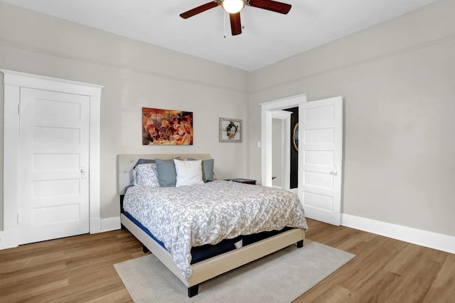 bedroom with a ceiling fan, baseboards, and light wood finished floors