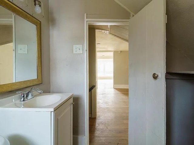 bathroom with vanity, lofted ceiling, and wood finished floors