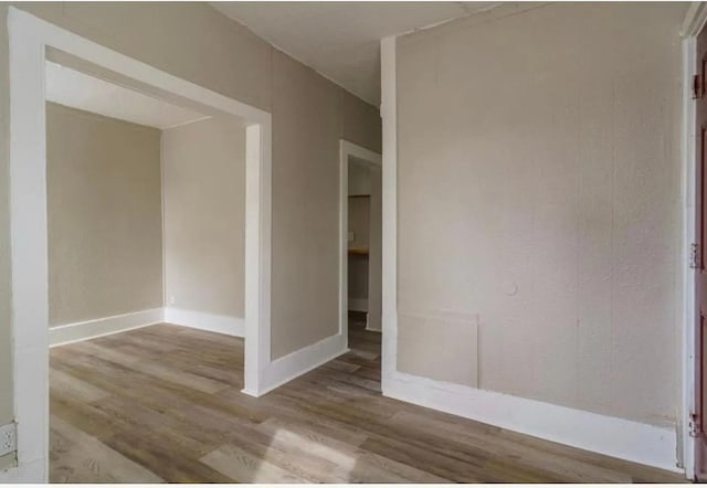 spare room featuring baseboards and wood finished floors