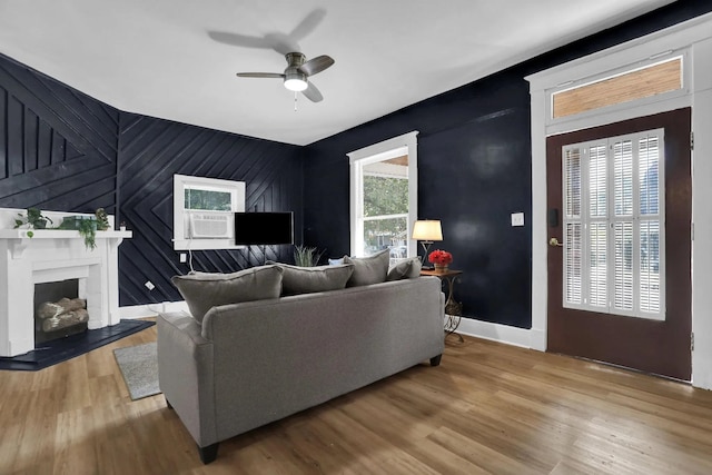 living room with a fireplace, wood finished floors, baseboards, and ceiling fan