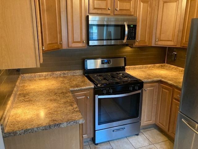 kitchen with light tile patterned floors, tasteful backsplash, and appliances with stainless steel finishes