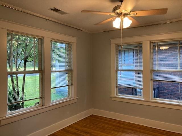 unfurnished room with visible vents, dark wood-type flooring, crown molding, baseboards, and ceiling fan