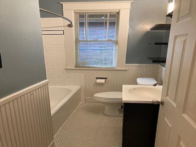 bathroom featuring toilet, wainscoting, tile patterned flooring, shower / bath combination, and vanity