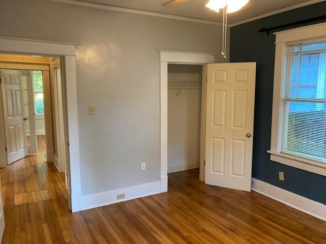 unfurnished bedroom with wood finished floors, baseboards, a closet, and ornamental molding