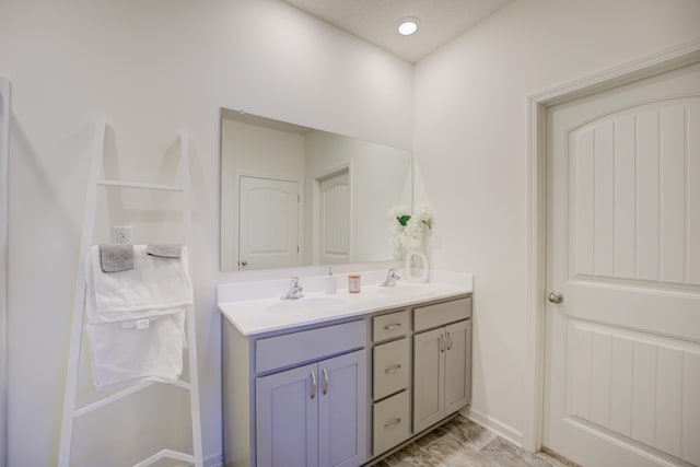 full bathroom featuring double vanity, baseboards, and a sink