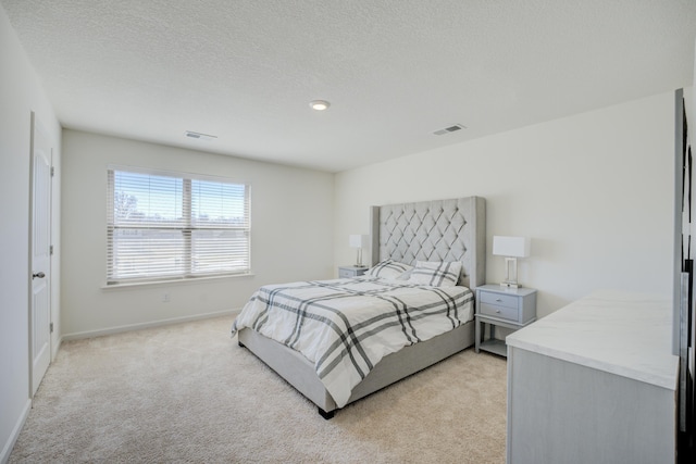 bedroom with visible vents, baseboards, light colored carpet, and a textured ceiling