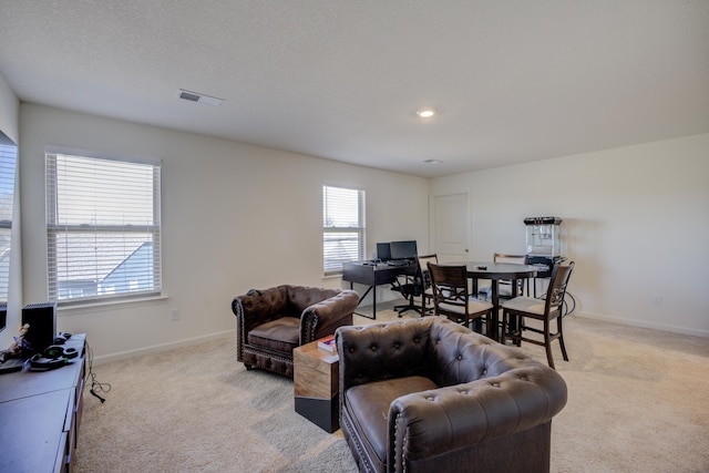 living area with light colored carpet, visible vents, and baseboards