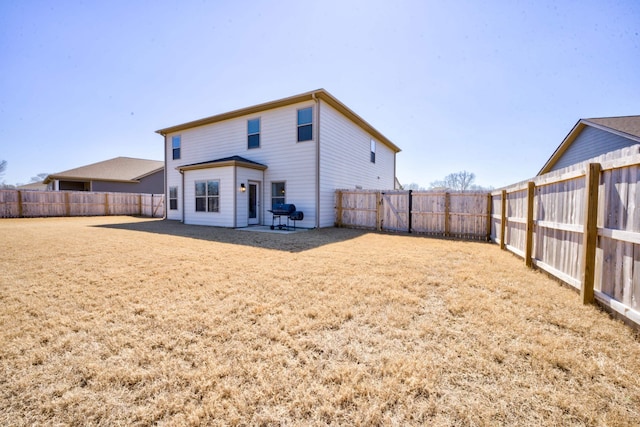 back of house with a lawn and a fenced backyard