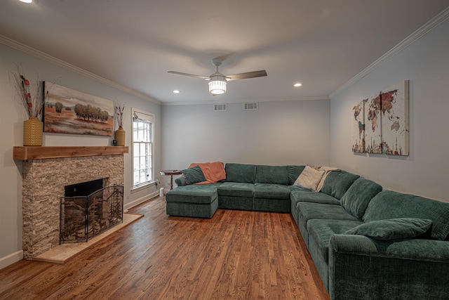 living area with a ceiling fan, wood finished floors, visible vents, and ornamental molding