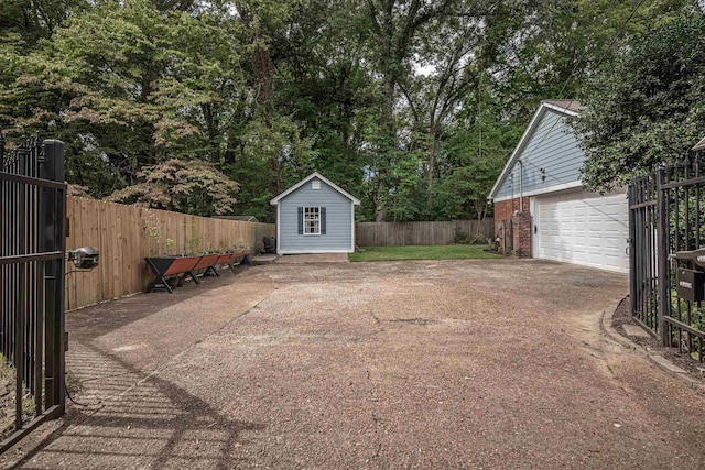 view of yard with a garage, an outbuilding, driveway, and fence