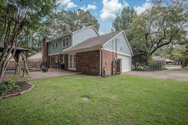 back of property featuring brick siding, fence, a lawn, french doors, and driveway