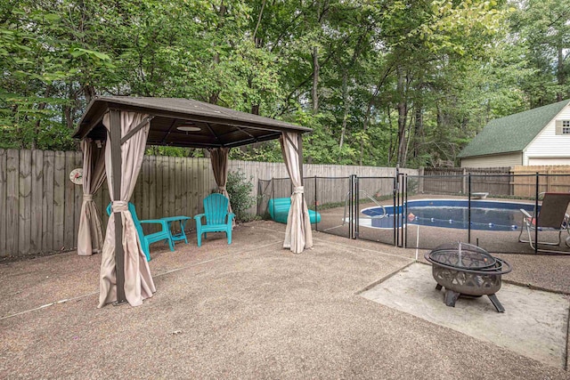 view of patio featuring a gazebo, a fenced in pool, a fenced backyard, and a fire pit