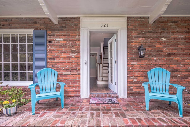 property entrance with a patio and brick siding