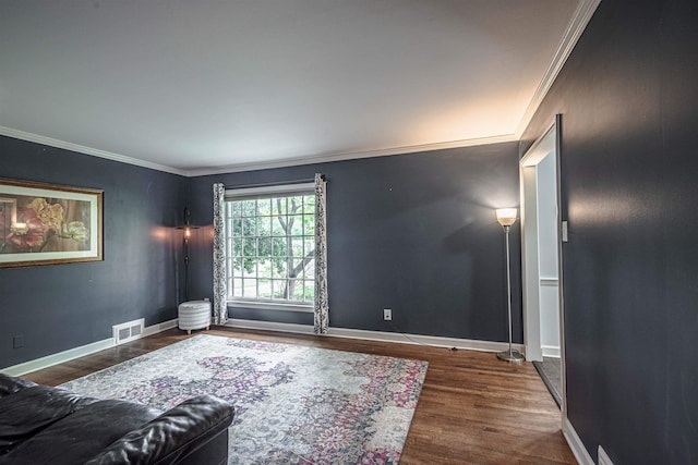 living area featuring visible vents, baseboards, wood finished floors, and ornamental molding